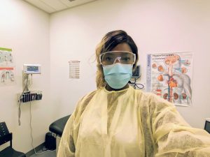 Denika McPherson in PPE, stands in clinical office
