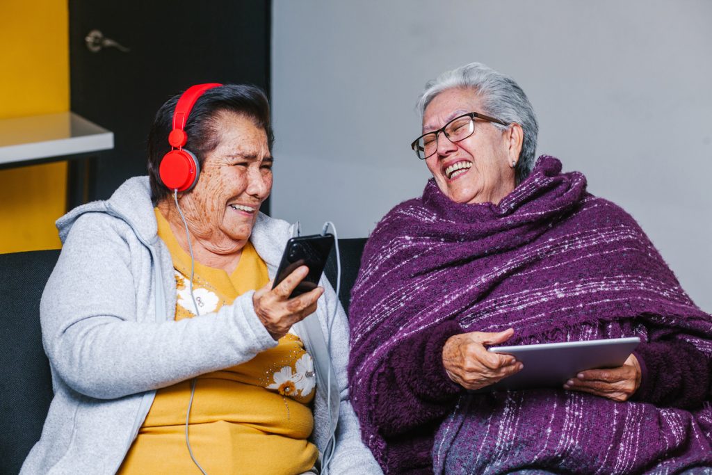 Latin Senior women listening music with headphones at home in Mexico city, mexican people