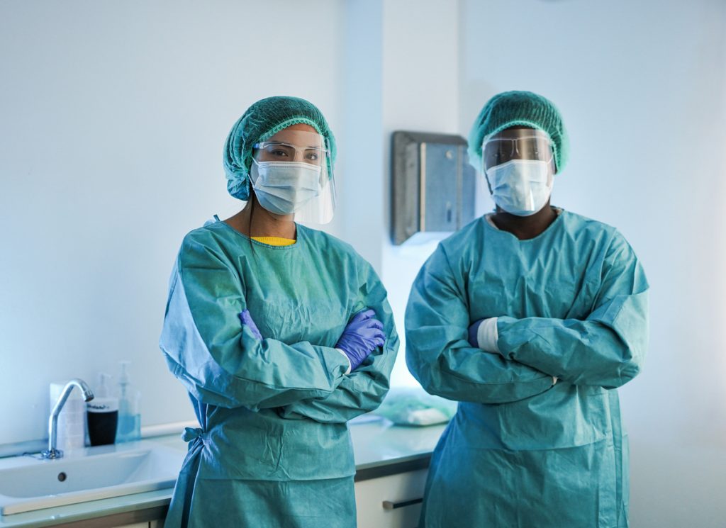 Multiracial medical workers wearing hazmat suit and protective face masks inside hospital laboratory