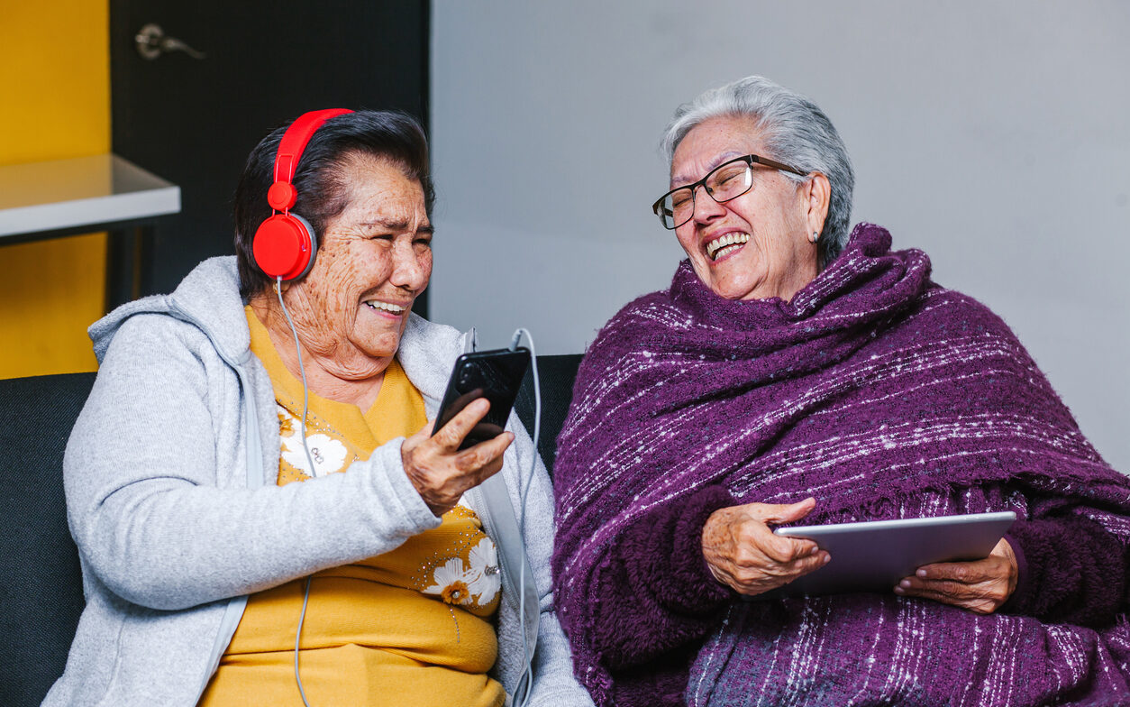 Latin Senior women listening music with headphones at home in Mexico city, mexican people